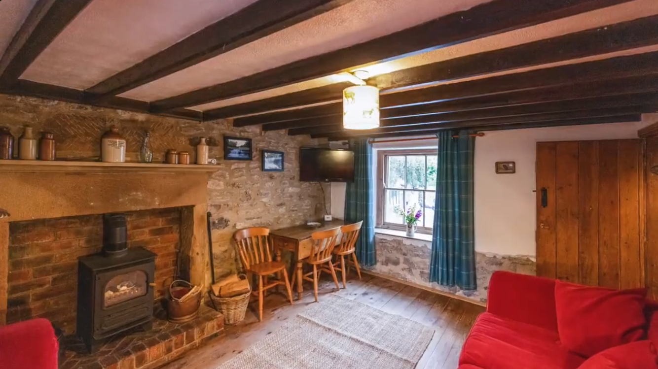 The real living room at Pumpkin Cottage with exposed beams, stone fireplace and log burner